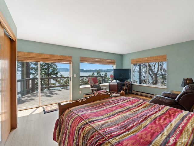 bedroom with access to outside, baseboard heating, wood-type flooring, and a closet