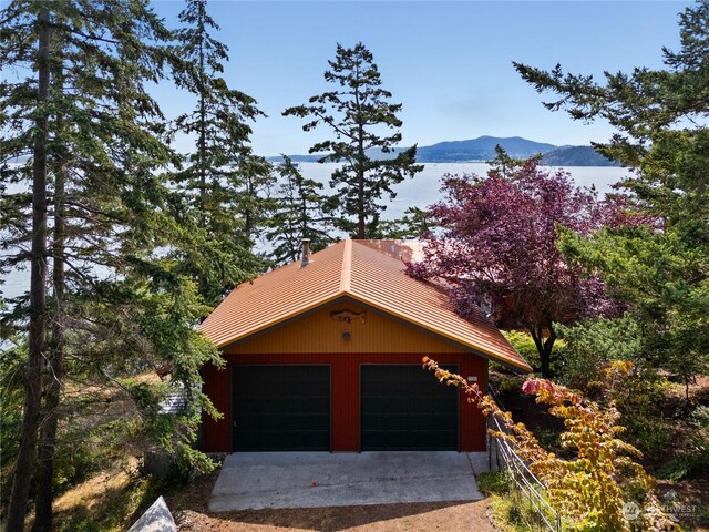 view of side of property with a water and mountain view, a garage, and an outdoor structure