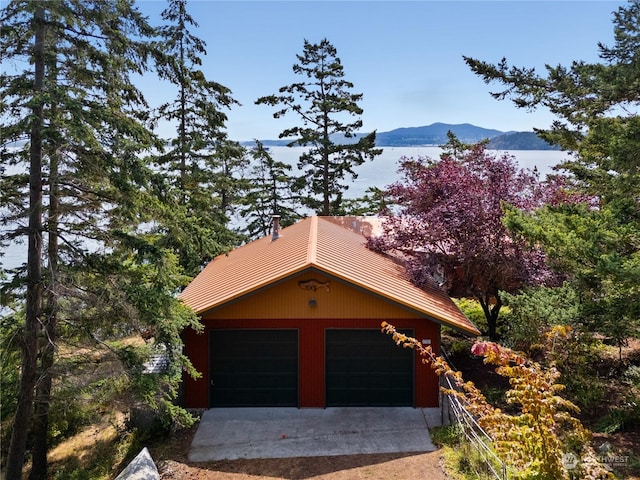 exterior space with an outbuilding, driveway, a water and mountain view, and a garage