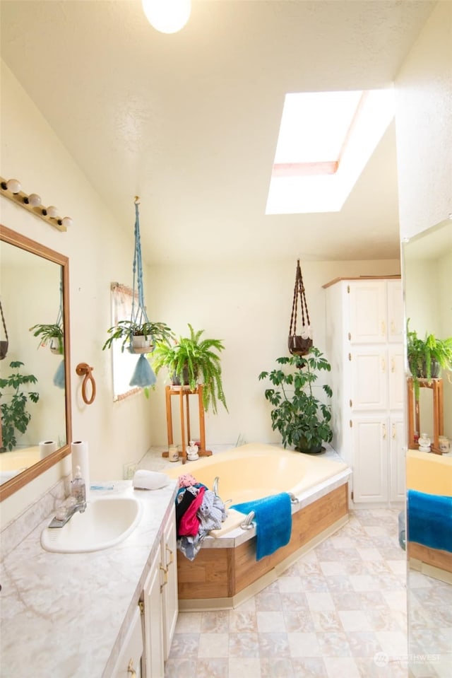 bathroom with tile patterned flooring, a bathtub, a skylight, and vanity