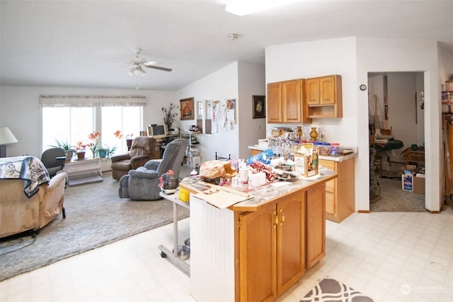 kitchen featuring ceiling fan, vaulted ceiling, light tile patterned floors, and a kitchen island