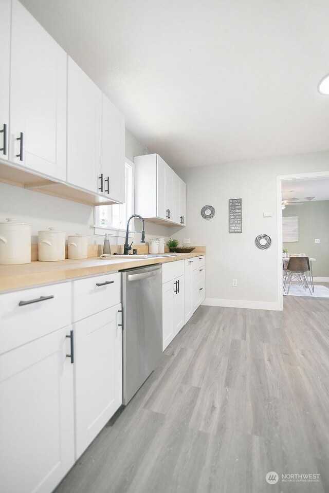 317 2nd Ave NW, Kelso, WA 98626 - kitchen with stainless steel dishwasher, white cabinets, light wood finished floors, baseboards, and light countertops