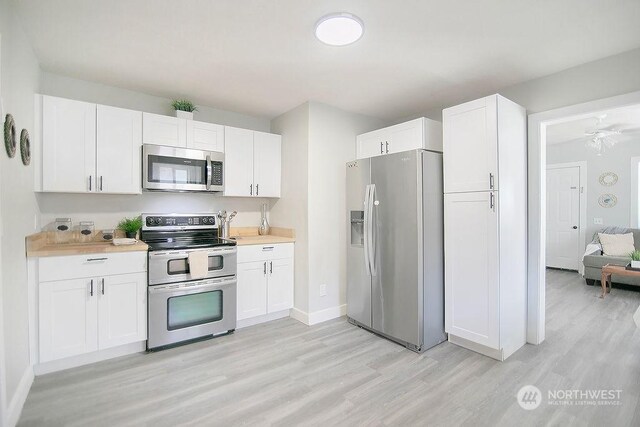 kitchen with white cabinets, light wood-type flooring, and stainless steel appliances