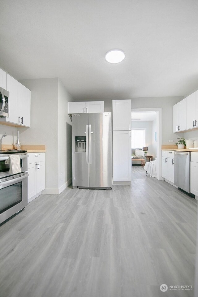 kitchen featuring stainless steel appliances, light hardwood / wood-style flooring, and white cabinets