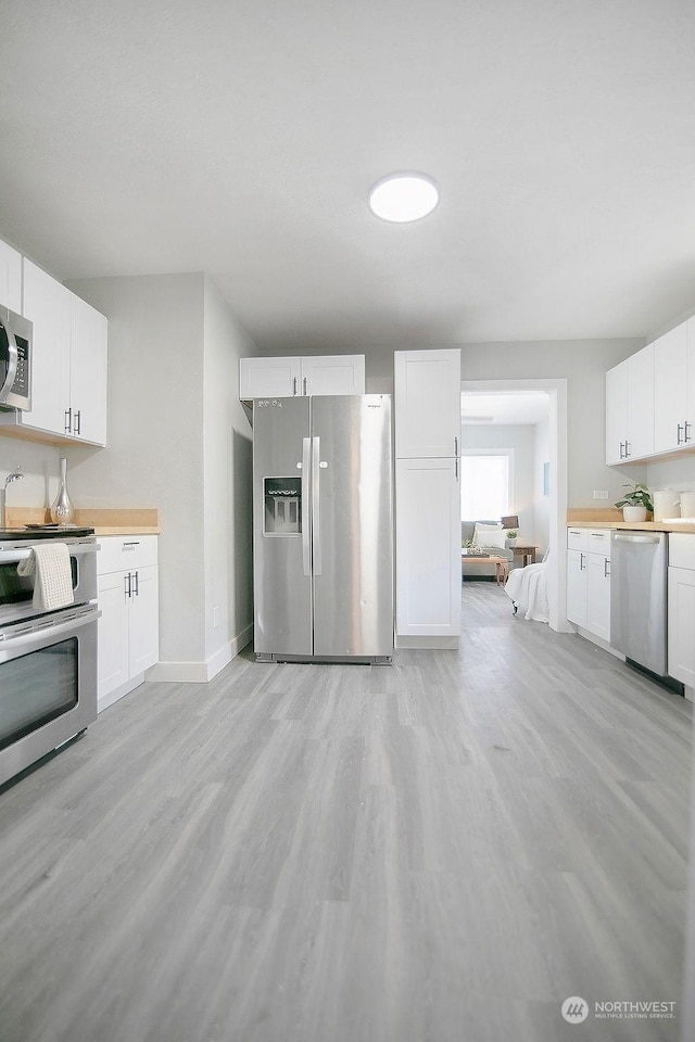 317 2nd Ave NW, Kelso, WA 98626 - kitchen with light wood-type flooring, wooden counters, appliances with stainless steel finishes, and white cabinets