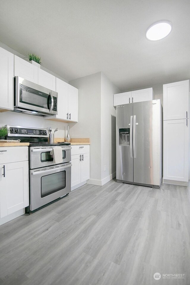 kitchen featuring light wood-type flooring, appliances with stainless steel finishes, and white cabinets