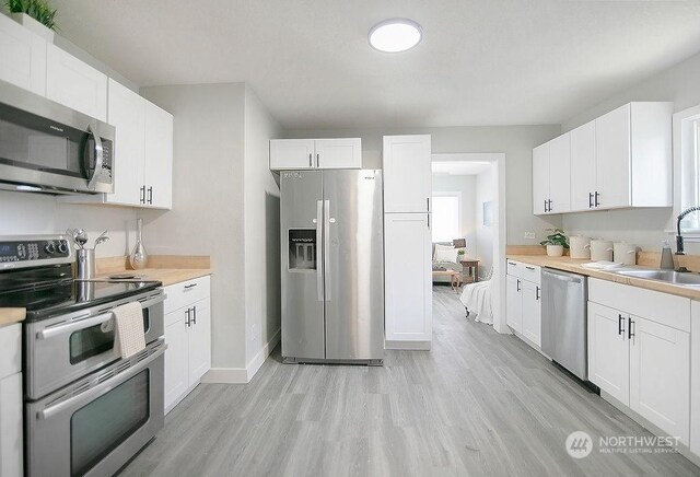 317 2nd Ave NW, Kelso, WA 98626 - kitchen featuring white cabinetry, stainless steel appliances, light countertops, and a sink