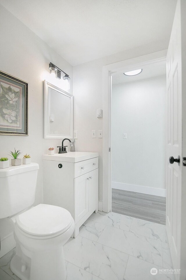 317 2nd Ave NW, Kelso, WA 98626 - bathroom with vanity, toilet, baseboards, and marble finish floor
