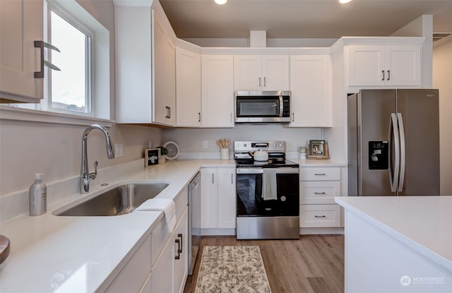 kitchen featuring sink, white cabinets, stainless steel appliances, and light wood-type flooring