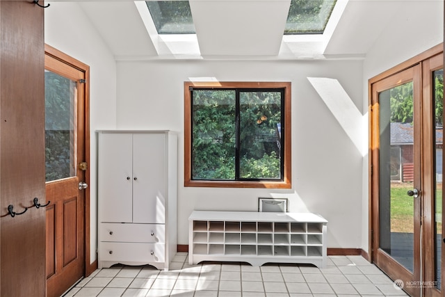 interior space with light tile patterned floors and lofted ceiling with skylight