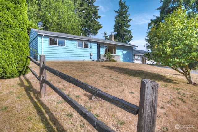 single story home with an attached garage, a chimney, a front yard, and fence