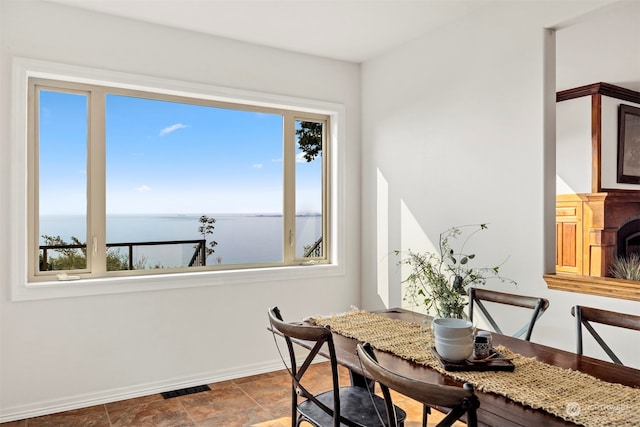 dining room with a water view and dark tile patterned flooring