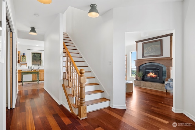 stairs featuring a tile fireplace, wood-type flooring, and a wealth of natural light