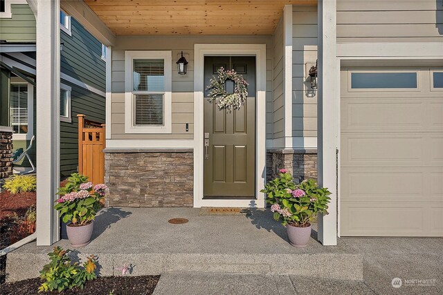 doorway to property with a garage and a porch