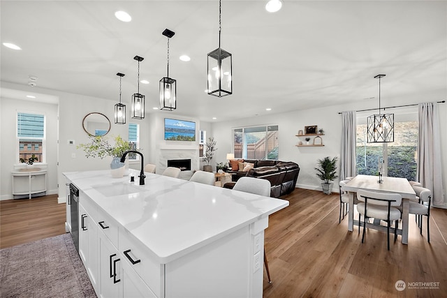 kitchen with white cabinetry, pendant lighting, sink, and a kitchen island with sink