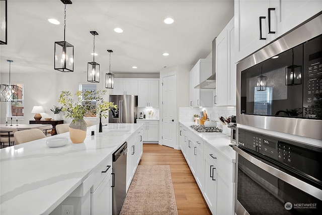 kitchen with appliances with stainless steel finishes, sink, pendant lighting, white cabinets, and light stone countertops