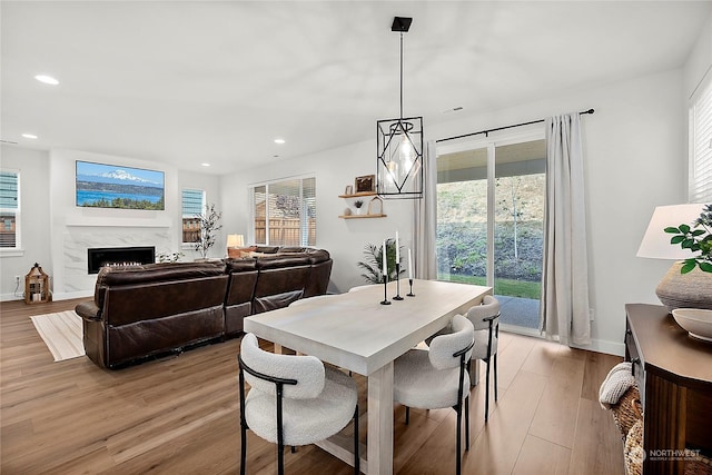 dining area with light hardwood / wood-style floors and a high end fireplace