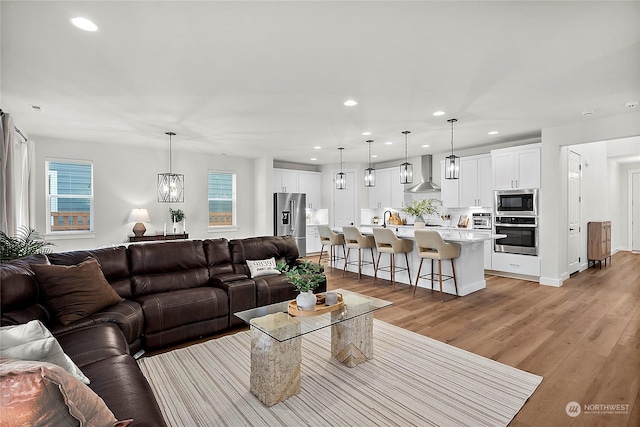 living room with sink, a chandelier, and light hardwood / wood-style floors