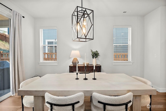 dining area with a notable chandelier and light hardwood / wood-style floors