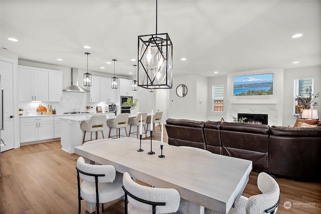 dining room featuring a high end fireplace and light hardwood / wood-style floors