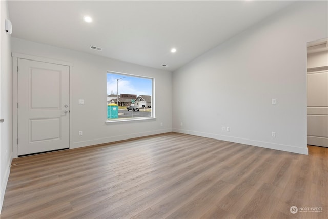 spare room with light hardwood / wood-style floors and lofted ceiling