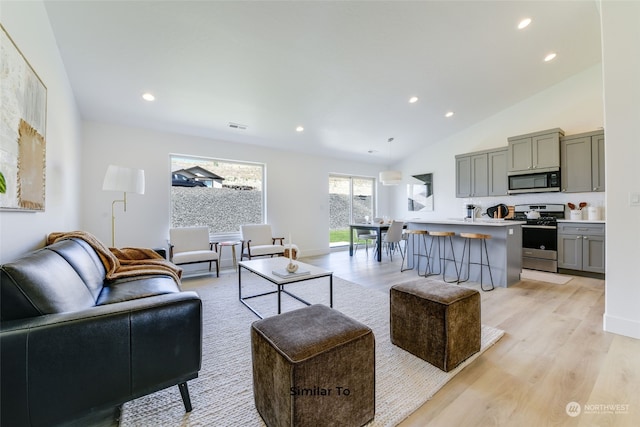 living room featuring high vaulted ceiling and light wood-type flooring