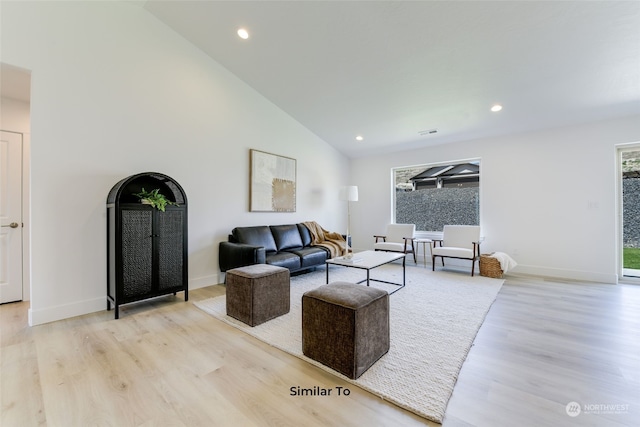 living room featuring high vaulted ceiling and light hardwood / wood-style flooring