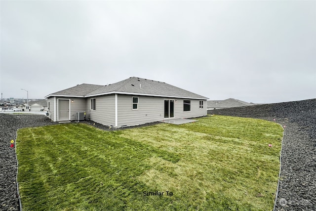 rear view of property featuring a yard, central AC unit, and a patio area