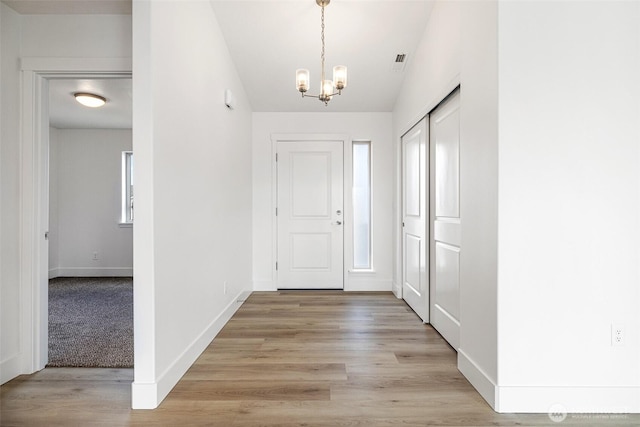 entryway with a chandelier, visible vents, light wood-style flooring, and baseboards