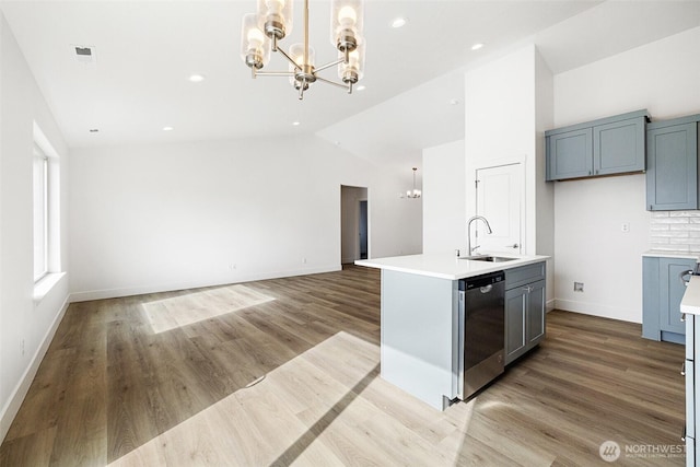 kitchen with dishwasher, light countertops, a sink, and a notable chandelier