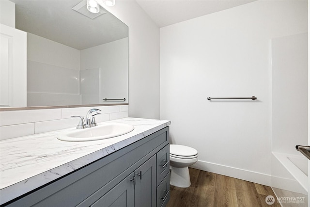 full bath featuring a tub to relax in, baseboards, toilet, wood finished floors, and vanity