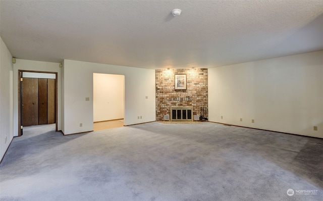 unfurnished living room with a brick fireplace, brick wall, a textured ceiling, and light carpet