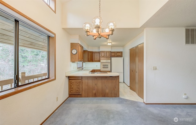 kitchen featuring light colored carpet, a notable chandelier, white refrigerator, kitchen peninsula, and decorative light fixtures