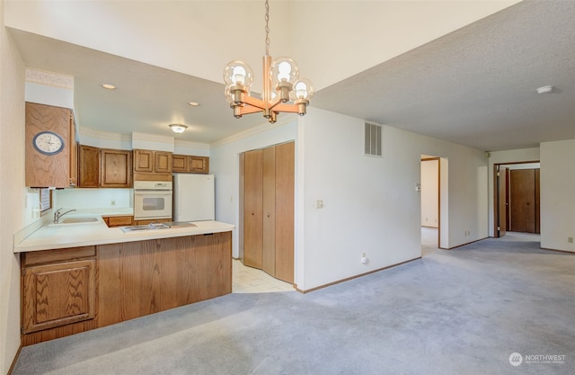 kitchen with white appliances, an inviting chandelier, light carpet, sink, and decorative light fixtures