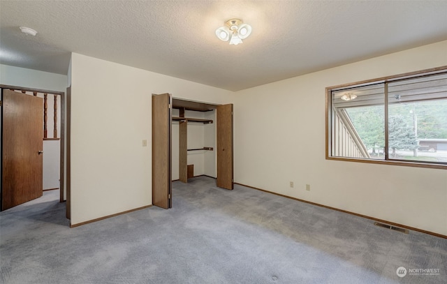 unfurnished bedroom with a textured ceiling, light colored carpet, and a closet