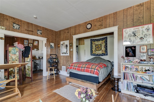 bedroom with wooden walls and hardwood / wood-style floors