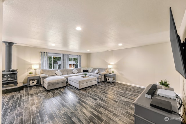 living room with a wood stove, a textured ceiling, and dark hardwood / wood-style floors