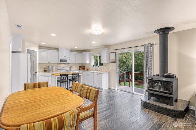 dining room featuring sink, a wood stove, and dark wood-type flooring