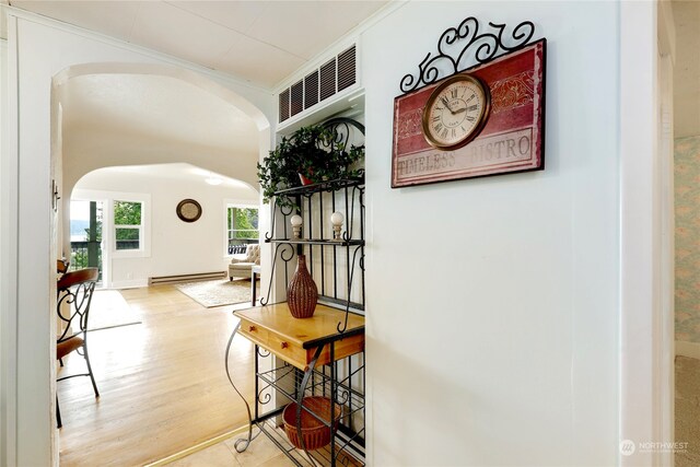 hallway featuring crown molding, a baseboard radiator, and wood-type flooring