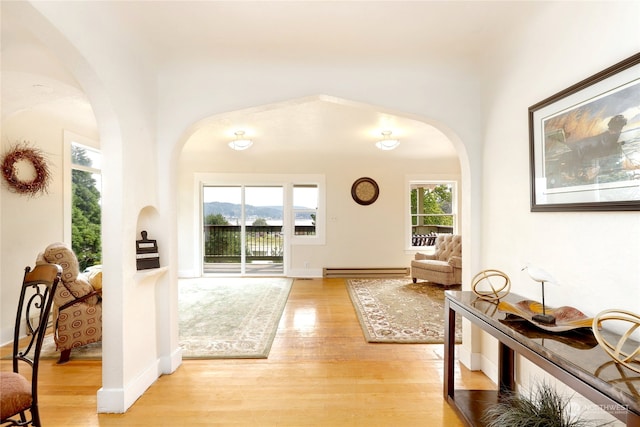 foyer entrance with plenty of natural light, a baseboard heating unit, and light hardwood / wood-style flooring