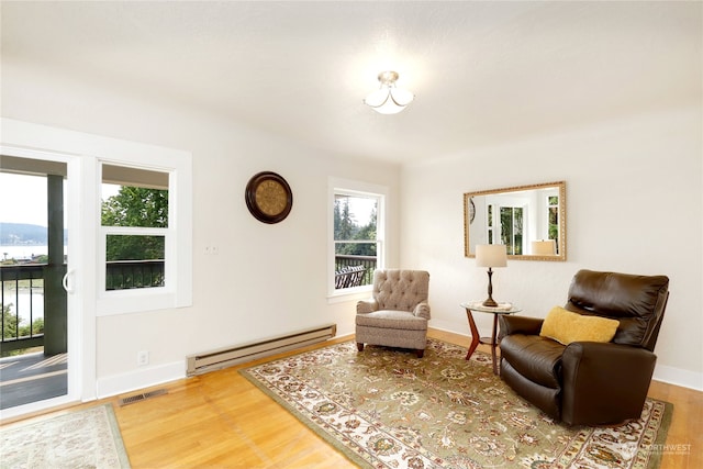 living area featuring baseboard heating and light hardwood / wood-style floors