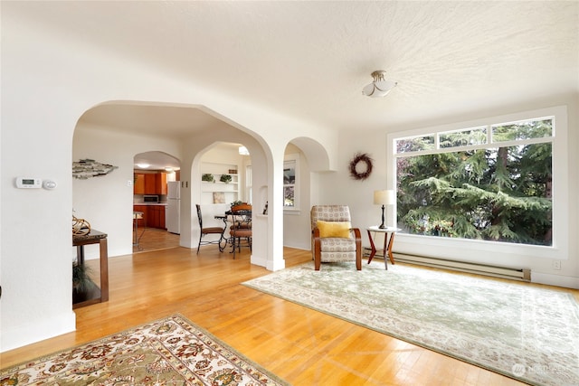 interior space featuring a textured ceiling, light hardwood / wood-style flooring, and baseboard heating