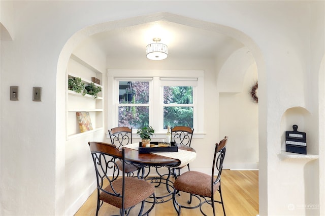 dining room with hardwood / wood-style flooring and built in shelves