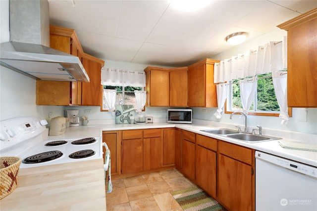 kitchen featuring dishwasher, wall chimney exhaust hood, sink, range, and light tile patterned floors