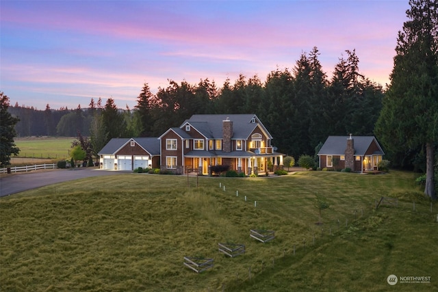 view of front of home featuring driveway, a chimney, a front lawn, and a wooded view