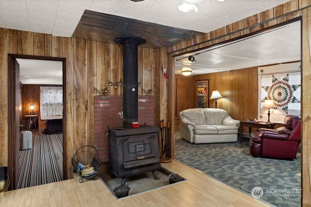 living room featuring wood walls, a wood stove, and wood-type flooring