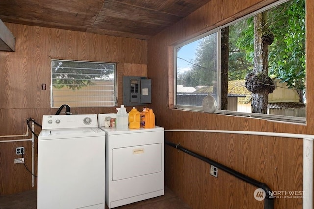 laundry room featuring wooden ceiling, wood walls, washing machine and clothes dryer, and electric panel