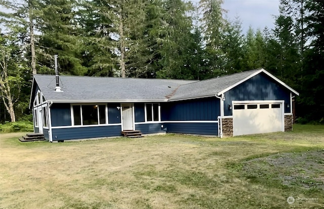 view of front of house with a garage, entry steps, stone siding, and a front yard