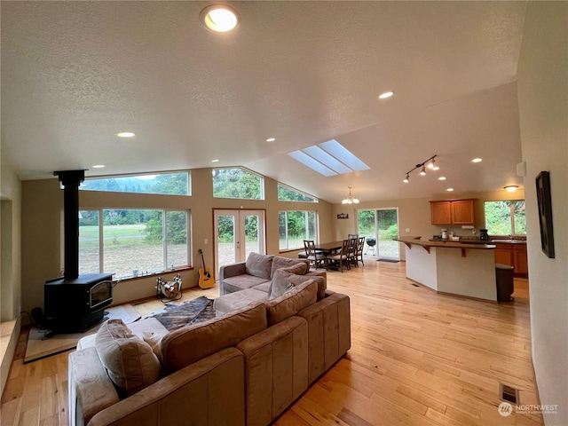 living room featuring visible vents, lofted ceiling with skylight, a textured ceiling, light wood-type flooring, and recessed lighting