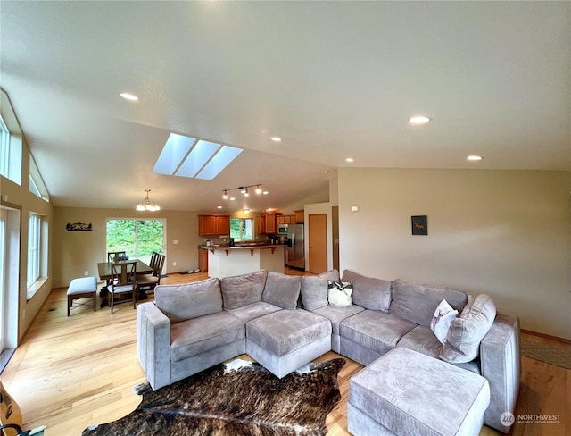 living room with lofted ceiling with skylight, recessed lighting, a notable chandelier, and light wood-style floors